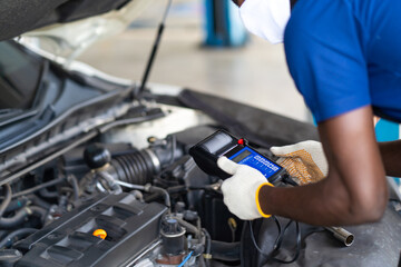 Expertise mechanic working in automobile repair garage. battery inspection. Battery Capacity Tester Voltmeter