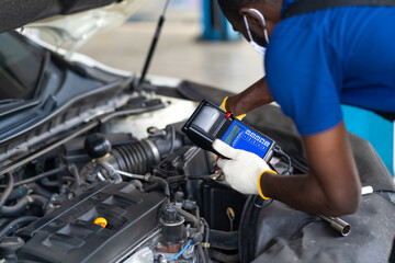 Fototapeta na wymiar Expertise mechanic working in automobile repair garage. battery inspection. Battery Capacity Tester Voltmeter