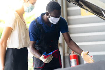 Mechanic man and woman customer wearing medical face mask protection coronavirus and check the car condition before delivery.