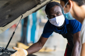 Mechanic man and woman customer wearing medical face mask protection coronavirus and check the car condition before delivery.