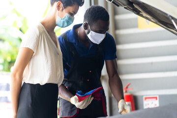 Mechanic man and woman customer wearing medical face mask protection coronavirus and check the car condition before delivery.