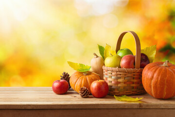 Thanksgiving holiday and autumn season concept with pumpkin, apples and fall leaves in basket on...