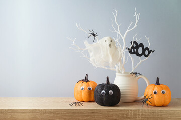Halloween holiday decorations with glitter pumpkin, spiders and ghost on wooden table.