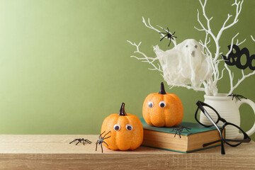 Halloween holiday concept with glitter pumpkin, book and ghost on wooden table.