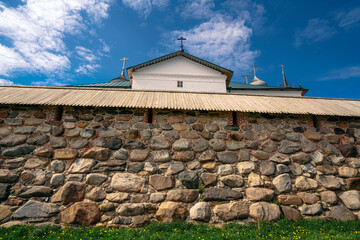 Fototapeta na wymiar View of the stone fortress wall of the Spaso-Preobrazhensky Solovetsky Monastery on a sunny cloudless summer day, Arkhangelsk region, Solovetsky Island, Russia