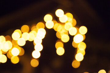 bokeh from a garland of yellow and orange circles on a dark black background