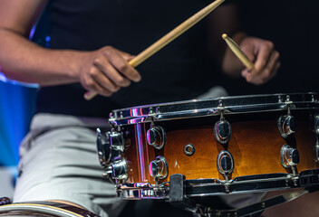 Close-up shot of a drummer playing a snare drum with sticks.