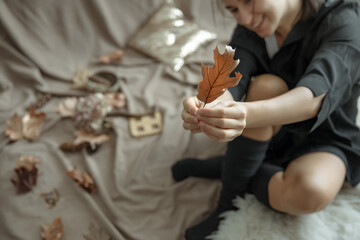 Girl holding an autumn leaf in her hands, a cozy autumn background.