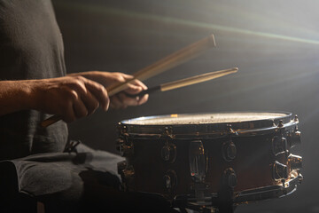 Close up drummer playing snare drum on dark background.