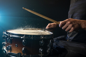 Close-up of a drummer playing a snare drum with splashing water.