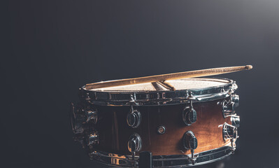 Close-up snare drum and drum sticks on a dark background.