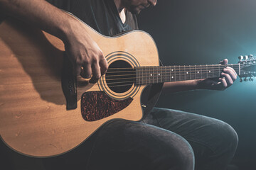 Obraz na płótnie Canvas Close-up shot of guitarist playing acoustic guitar, copy space.