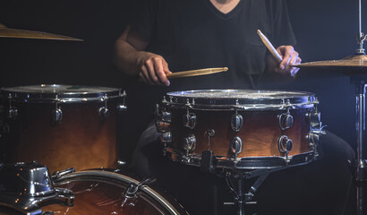 A male drummer plays a drum kit on stage.