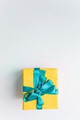 present gift box wrapped with yellow paper and blue ribbon