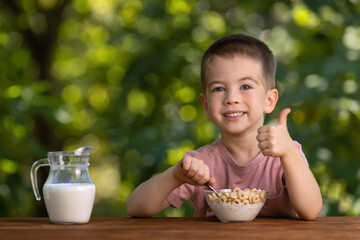 little boy eating corn flakes on breakfast outdoors