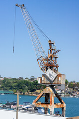 Fototapeta premium View of crane near marina on Cockatoo Island with houses in background, Sydney, NSW, Australia