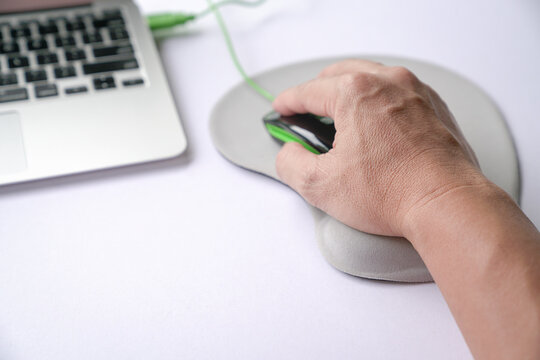 Man's hand clicking on mouse, resting his wrist on wrist rest or support memory foam. Close up shot.
