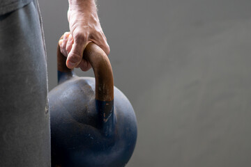 Close-up of athletic man holding kettlebell weight at home gym