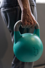 Close-up of athletic man holding kettlebell weight at home gym