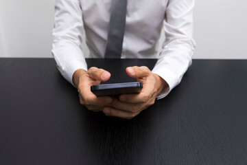 Close up of business man hands using smartphone on a black wood table.
