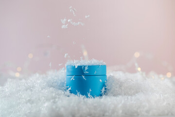 Bright blue blank jar of winter protective cosmetic product in artificial snow 