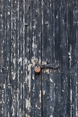 Old wooden doors with peeling paint, locked with a clasp and rusty padlock