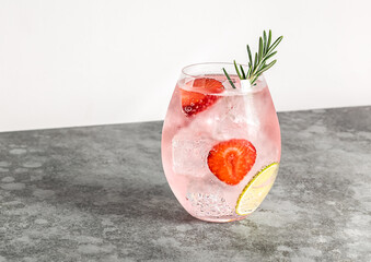 Premium pink gin with strawberry, lime, and rosemary. Refreshing alcohol cocktail with ice.  - obrazy, fototapety, plakaty