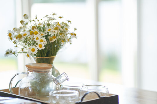 Beautiful white daisy flowers in a glass vase on the kitchen table near the window. Flower arrangement in the home interior, decor. High quality photo