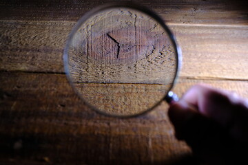 hand holding magnifying glass on wooden background