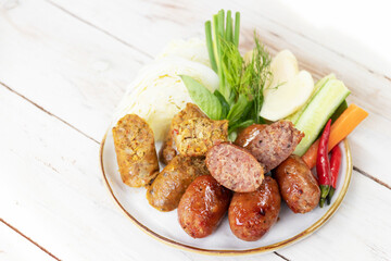 Northern Thai spicy sausage (Sai Aua) and Thai style grilled pork sausages on dish with fresh vegetable, herb and chili. Delicious appetizer Thai style.