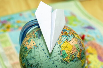 paper airplane on a globe on the background of a world map travel tourism concept