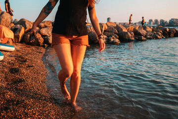 A woman with a club foot steps on the seashore. Legs close-up. The concept of clubfoot and arthritis