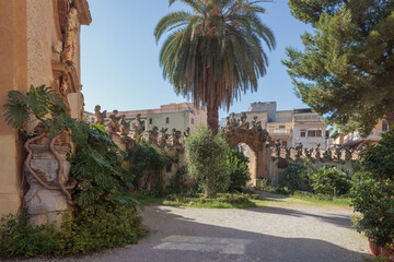 Fototapeta na wymiar Bagheria, Sicilia. Villa Palagonia detta la villa dei mostri.. Sculture simboliche sul muro di cinta del giardino con palma. 