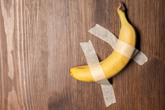 Yellow Sweet Banana On The Wall. Banana Duct Taped To The White Wall.