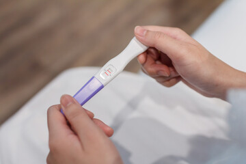Hand holding the pregnancy test is showing a positive result.