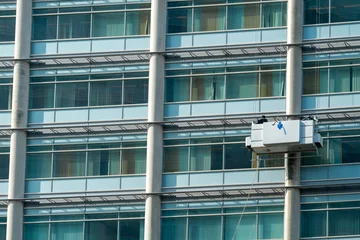 Fototapeten Window cleaners at work at a great height in a gondola at the uwv building in Amsterdam Sloterdijk, Noord-Holland Province, The Netherlands © Holland-PhotostockNL