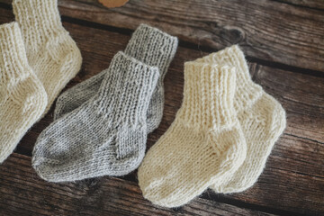Fototapeta na wymiar Hand knitted baby socks, made of organic sheep wool yarn, on dark wooden background, vintage style