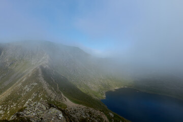 Mist lifting off Striding Edge in the Lake District, shot in landscape looking towards Helvellyn with the blue water of Red Tarn on the right had side