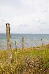 Reinforced concrete posts with stretched old barbed wire. View of the Black Sea.