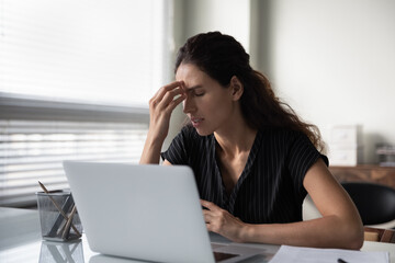 Sad frustrated millennial woman tired of work at computer, feeling unwell, suffering from stress, headache, dry irritable eyes. Businesswoman touching head at workplace. Fatigue, burnout concept - obrazy, fototapety, plakaty