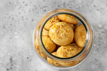 Homemade Norwegian butter cookies with almonds in a glass jar on a light gray culinary background. Traditional Scandinavian pastries top view