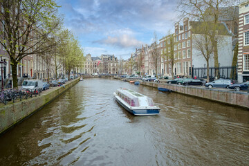 Fototapeta premium A canal boat sails through the Herengracht in Amsterdam, Noord-Holland province, The Netherlands