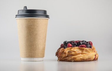 Delicious berries pastries with paper disposable coffee cup on a white background. Breakfast