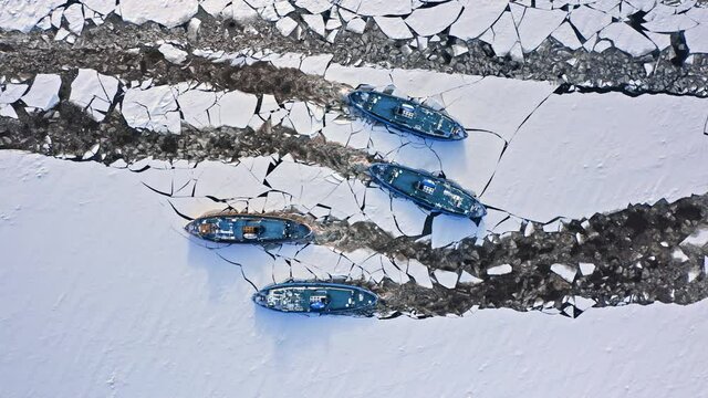 Four icebreakers crushing ice on river. Aerial view of winter.