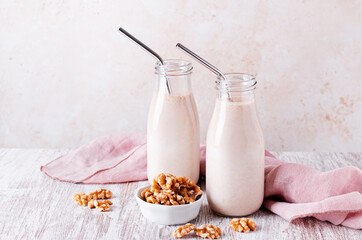 Walnut milk in glass bottles with reusable metal drinking straw