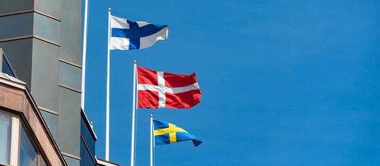 Naklejka premium Group of scandinavian flags consist of Finland, Sweden and Denmark on the top of building.