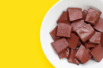 Pork blood pudding in white bowl on yellow background.