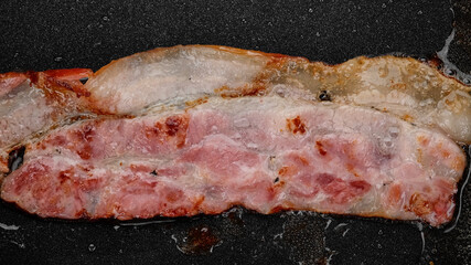 Fry bacon, macro. Bacon in frying pan, top view. Traditional breakfast with bacon