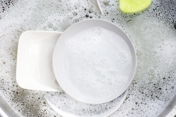 Washing dishes, Close up of utensils soaking in kitchen sink.