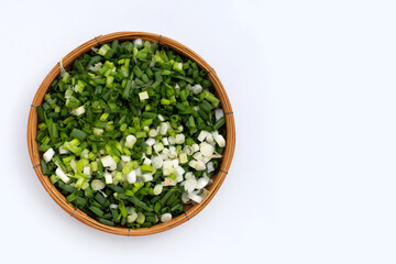 Chopped spring onions in bamboo basket on white background.